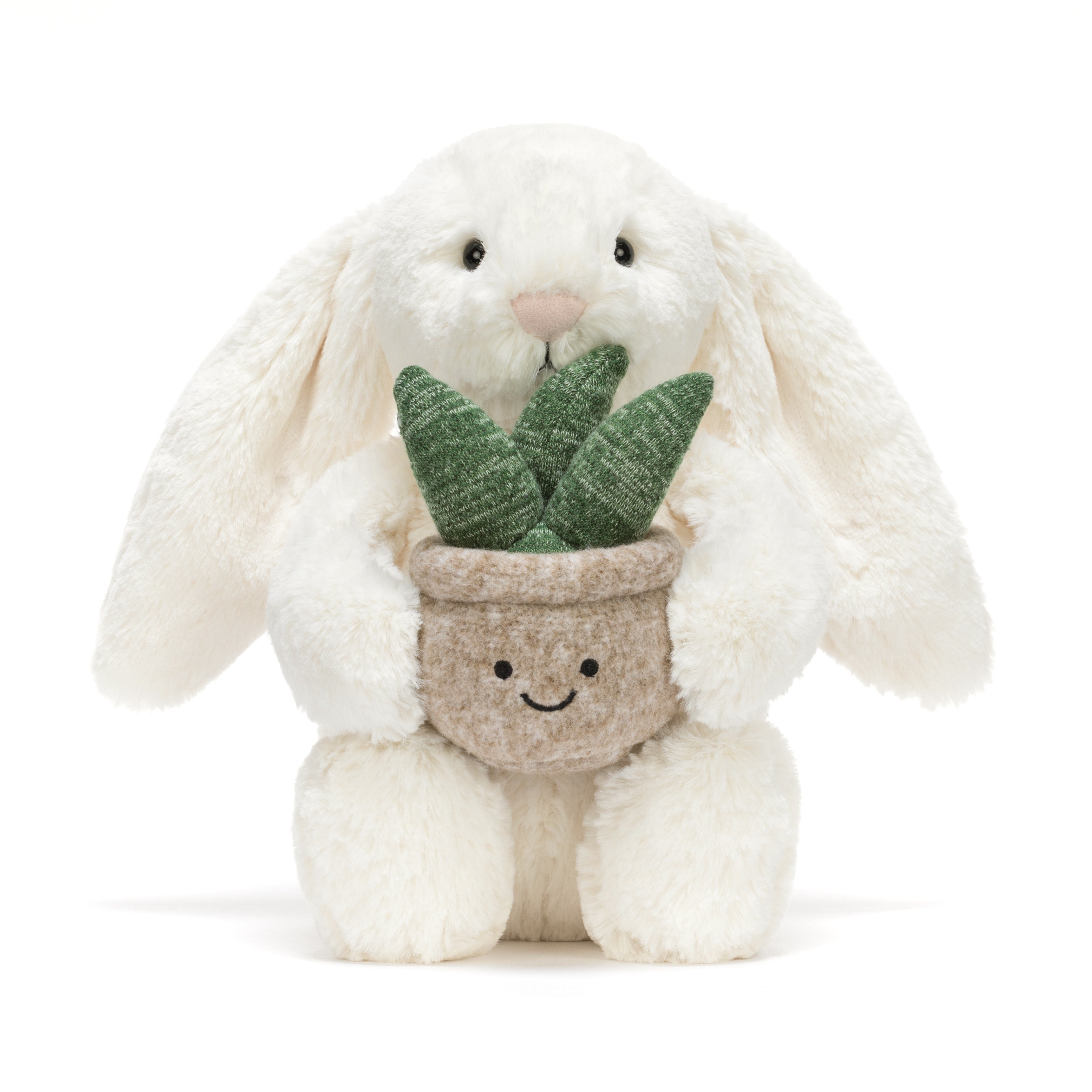 peluche lapin crème Jellycat avec plante posée sur une table décorative - Jellycat cream bunny plush with plant sitting on a decorative table