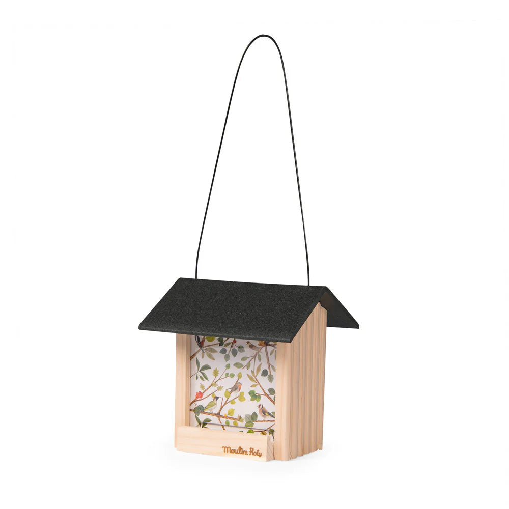 Mangeoire à oiseaux Le Botaniste de Moulin Roty en bois avec toit recyclé installée dans un jardin pour nourrir les oiseaux - Moulin Roty Le Botaniste wooden bird feeder with recycled roof designed for feeding garden birds