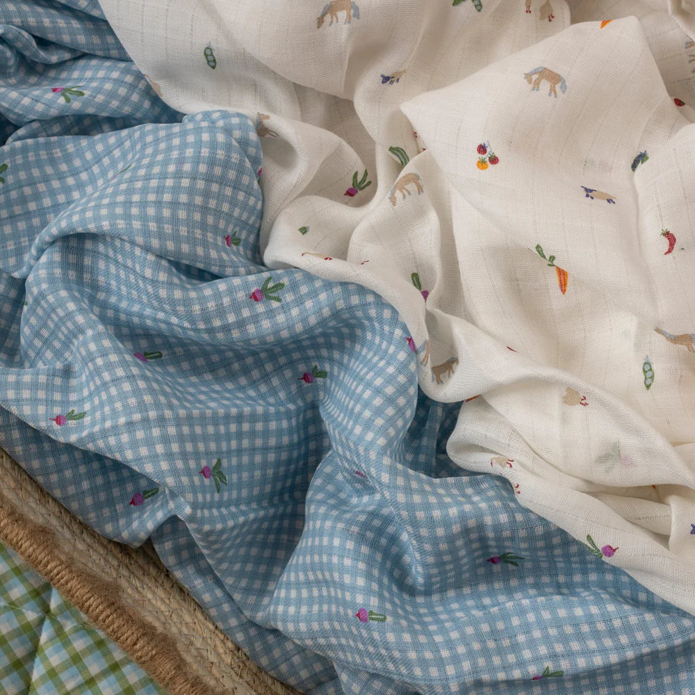 Duo de mousselines bébé Avery Row en coton organique motifs petite ferme et radis pliées sur surface douce - Avery Row organic cotton muslin swaddle set with farm and radish prints folded on soft surface